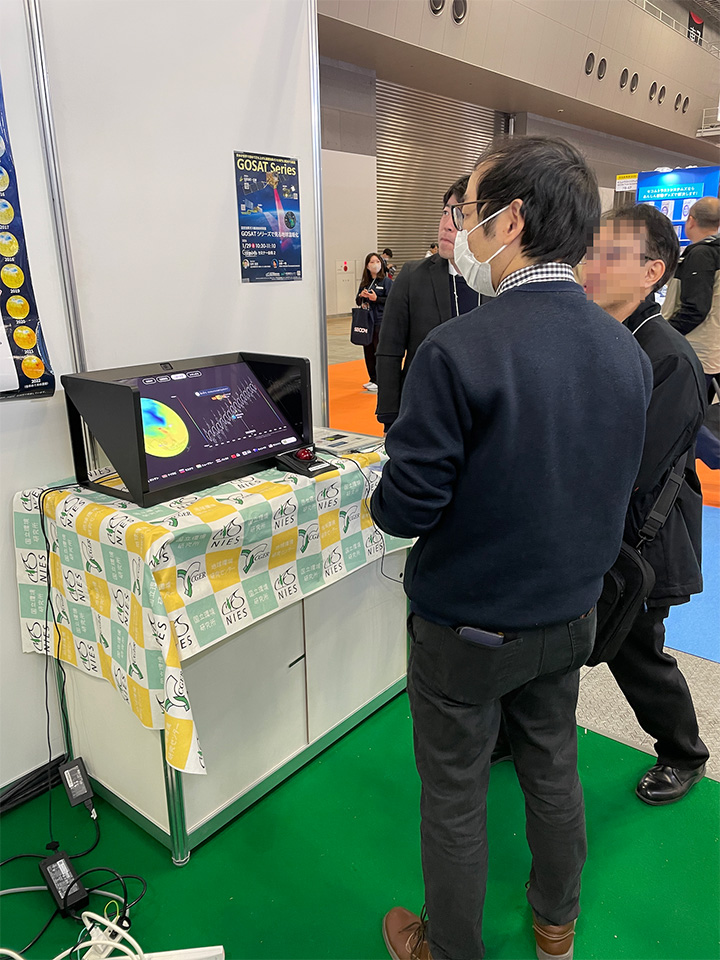 GOSAT 3Dビジュアライザーの前で来場者へ説明するNIES地球システム領域の中岡主任研究員と環境省地球環境局総務課気候変動観測研究戦略室の環境専門調査員・末松様