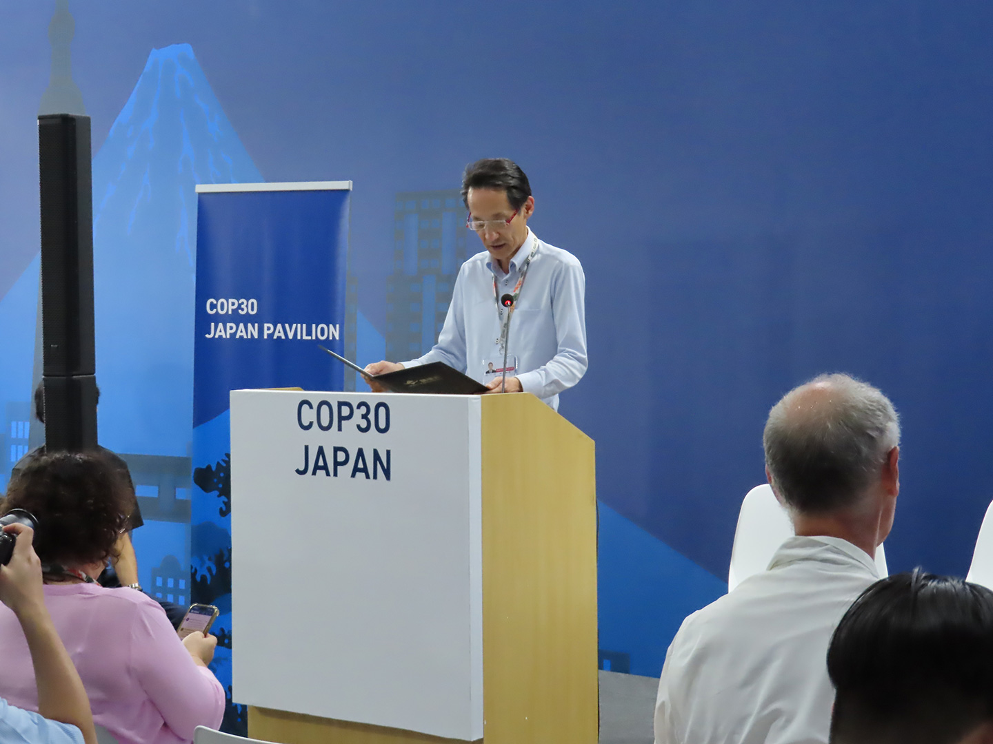 開会の挨拶をする土居地球環境審議官（環境省）。ジャパンパビリオンは白と青を基調としたブースでした。